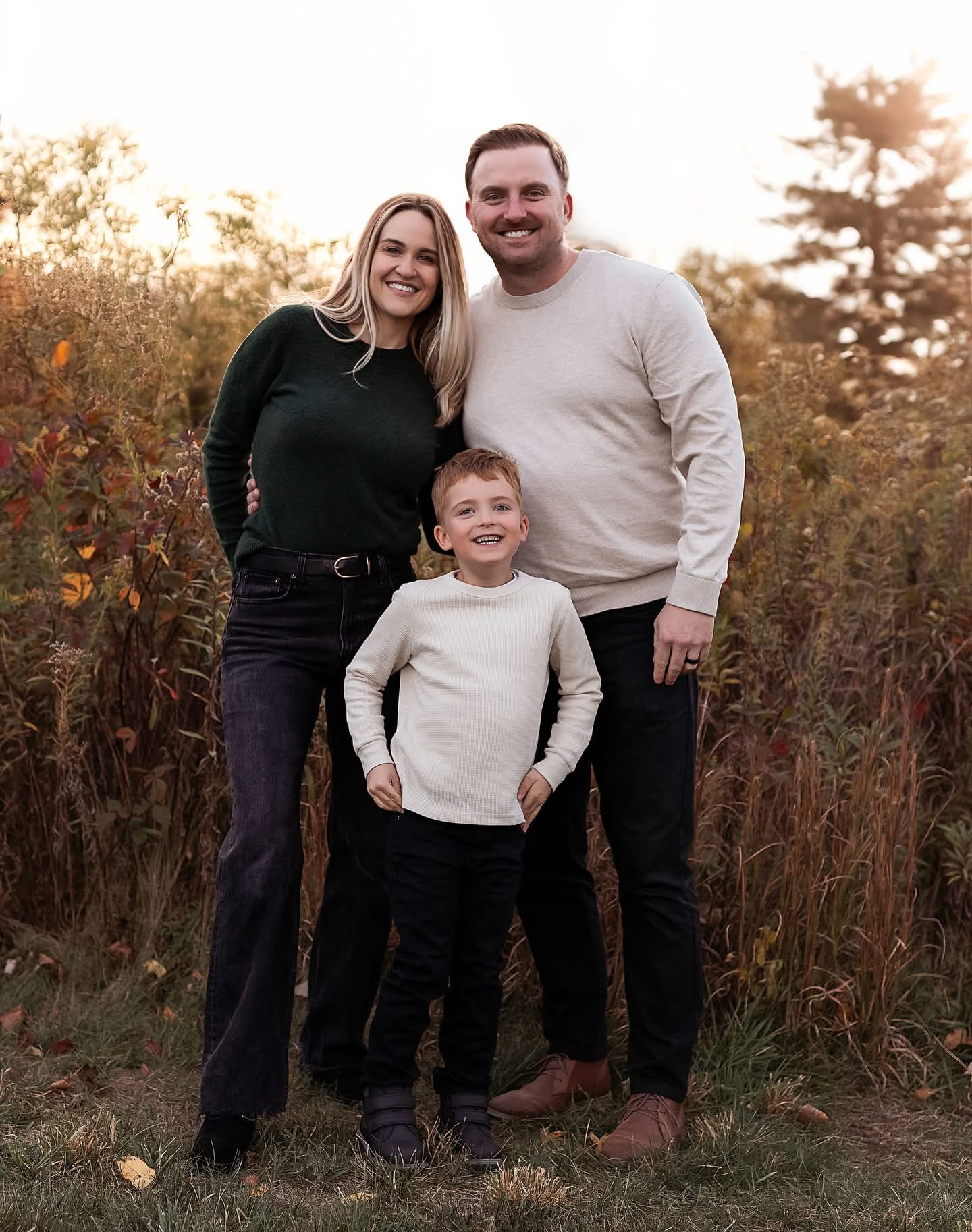 Jon Dages with his wife and son in an Indianapolis field at sunset
